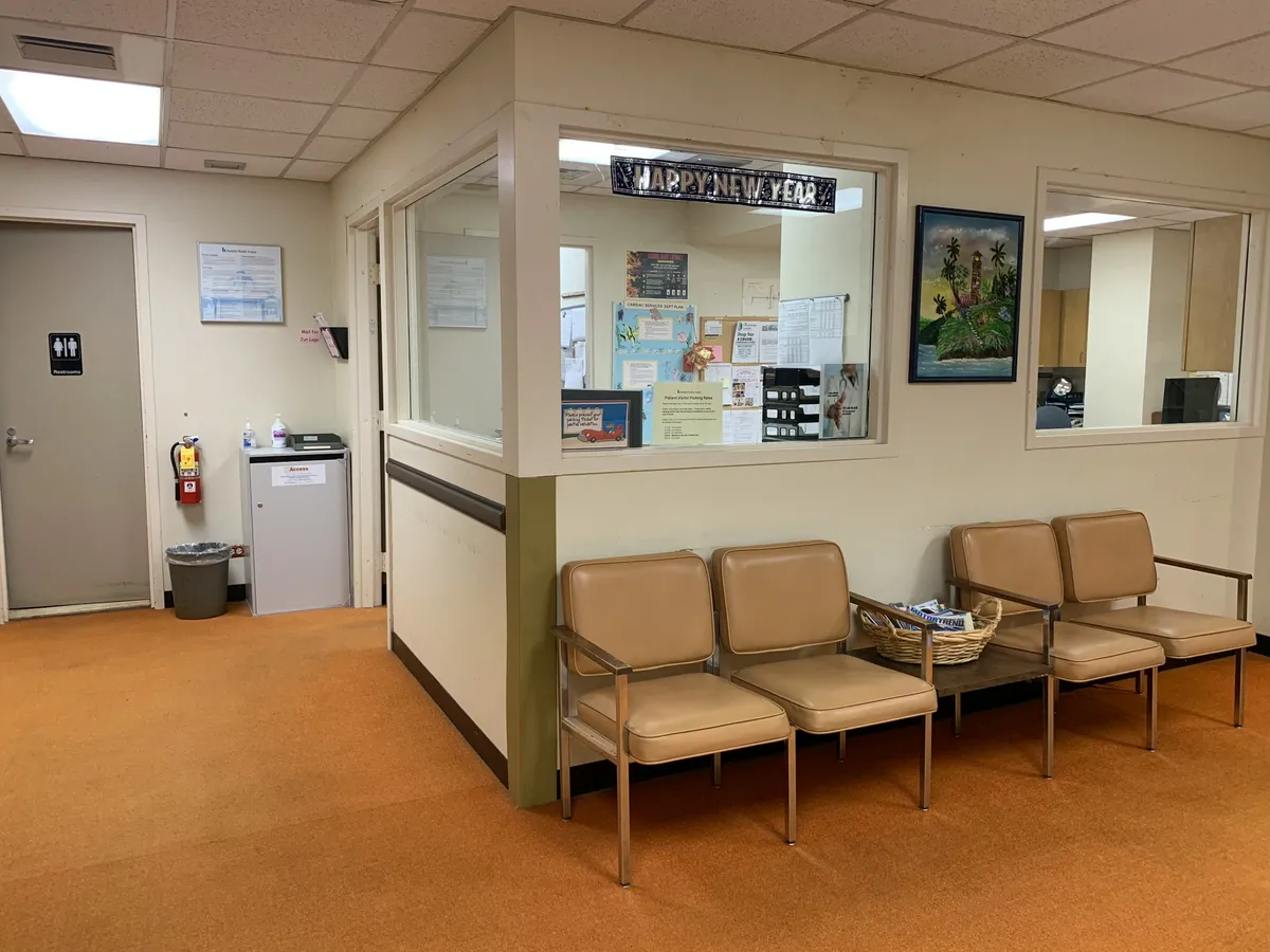 A quiet waiting area with brown and white padded armchairs along a wall